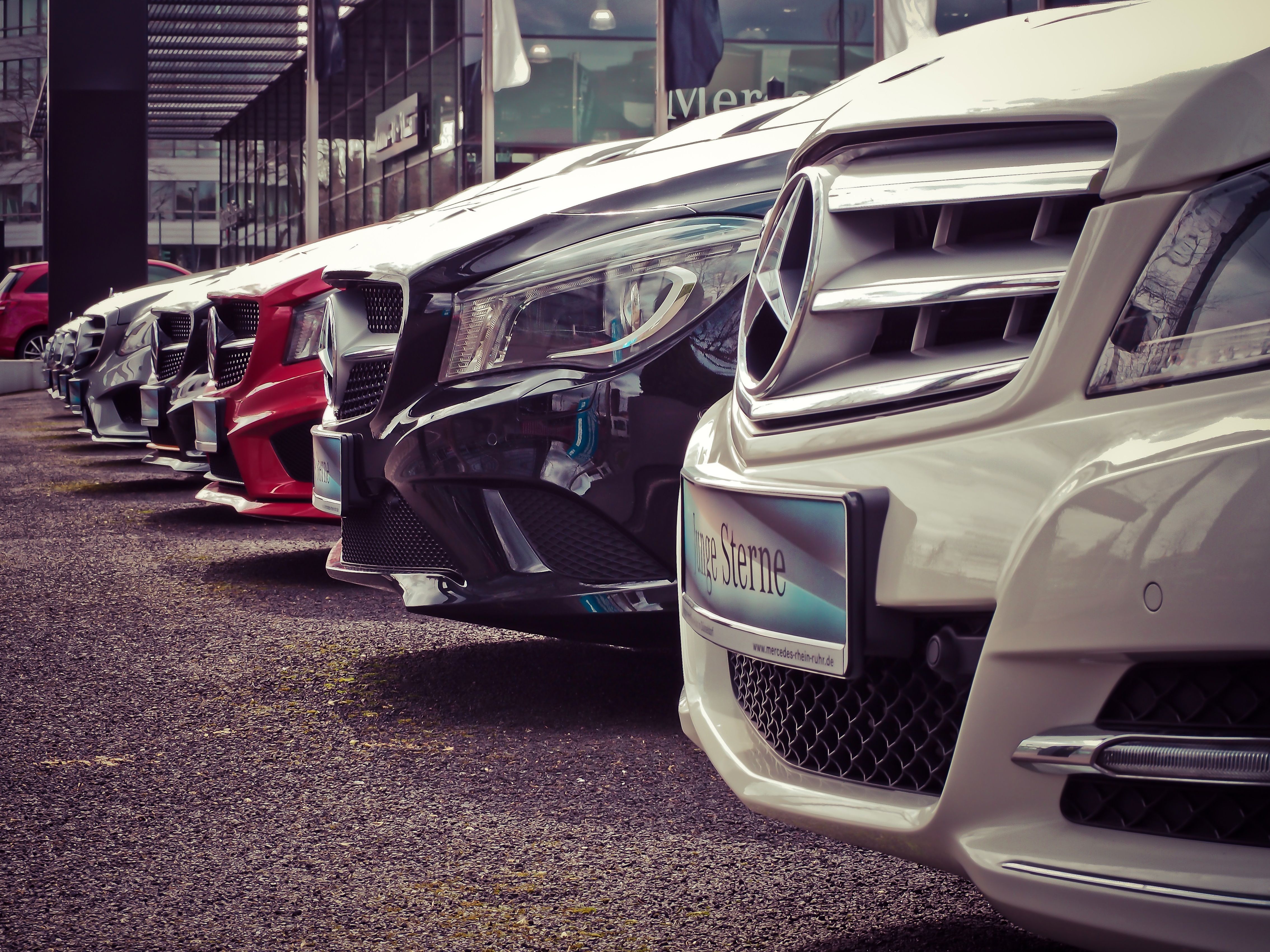Row of cars lined up at an outdoor dealership lot