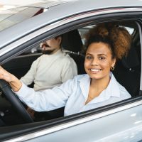 Woman test driving a new car at a dealership, evaluating it for a review