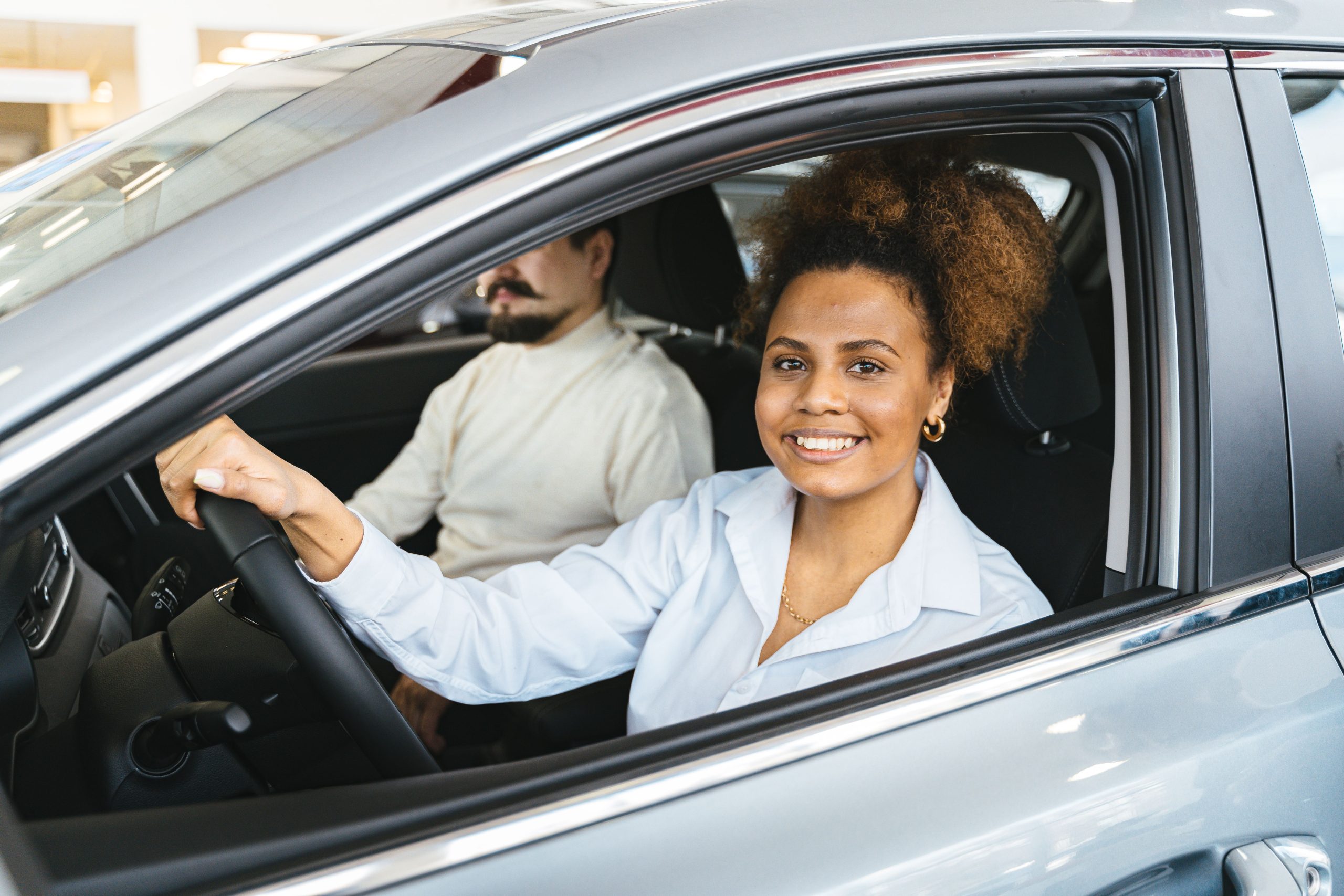 Woman test driving a new car at a dealership, evaluating it for a review